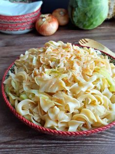 a bowl filled with pasta and vegetables on top of a wooden table