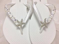 This beautiful white flip flops is wrapped with white satin ribbon and adorned with a silver tone Starfish with rhinestones. The straps are embellished with pearls and rhinestones. Ribbon is white, if you are needing other colors of ribbon please color chart. All flip flops are handmade to order and the production time is 5-7 business days and then please allow additional time for shipping. Amazing for beach, weddings, flower girl or a fancy event, you choose! Please choose your size from the dr White Summer Flip Flops As Gift, White Flip Flops As Summer Gift, Elegant Silver Beach Flip Flops, Adjustable White Flip Flops For Wedding, White Adjustable Flip Flops For Wedding, White Open Toe Flip Flops For Wedding, White Open Toe Flip Flops For Party, Adjustable White Sandals For Beach Wedding, White Sandals With Rhinestones And Adjustable Fit