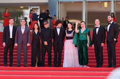 a group of people standing next to each other on top of a red carpeted staircase