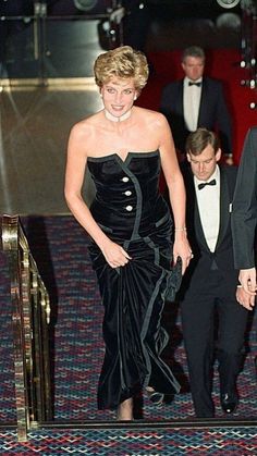 a woman in a black dress walking down a red carpet