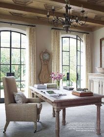 a living room filled with furniture and windows next to a table in front of a fireplace