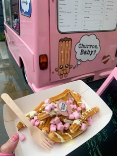 a waffle topped with marshmallows in front of a pink food truck