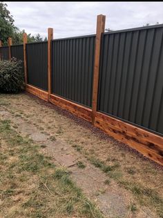 the fence is made out of metal and wooden planks, along with some grass