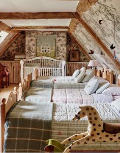 there are two beds in the attic with blankets on them and a stuffed giraffe