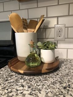 a kitchen counter with wooden utensils and a bottle on the tray next to it