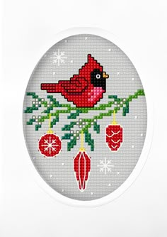 a cross stitch christmas ornament with a cardinal on it