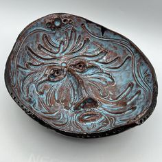 a blue and brown bowl with a face on it