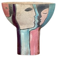 a ceramic vase with faces painted on it