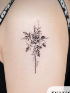 a cross with a rose tattoo on the back of a woman's upper arm