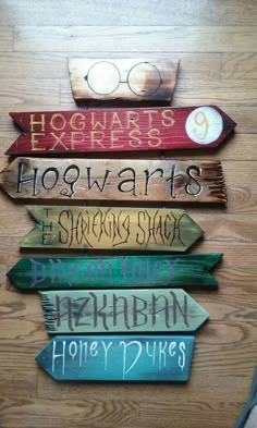 some wooden signs that are on top of a wood table and one is pointing to hogwarts