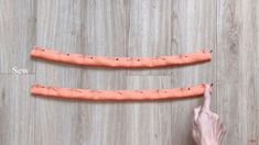 two fingers pointing at an orange object on a wooden floor with measurements for each piece