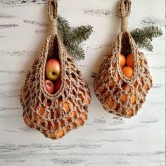 two bags filled with fruit sitting on top of a white wooden table next to a pine tree