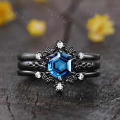 a ring with blue and white stones on it sitting on top of a piece of wood