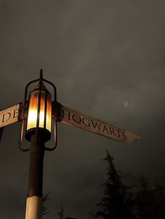 a lamp post with two street signs on it and a cloudy sky in the background