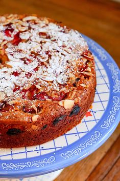 a cake on a blue and white plate topped with nuts, cranberry sauce and powdered sugar