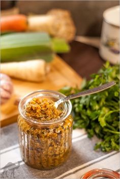 a jar filled with food sitting on top of a table next to vegetables and a knife