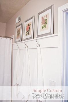 bathroom with towels hanging on the wall and three framed pictures above shower curtain rod holders