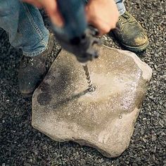 a man using a drill to fix a rock on the ground with a power drill