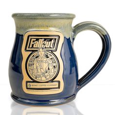 The front of the Bones Coffee Company Lucy hand thrown mug with the Atomic Apple art on the golden medallion. It is inspired by Zenimax and Amazon’s Fallout show. The mug is powder blue colored with a white and yellow glaze on top. Fallout Merch, Fallout Merchandise, Bones Coffee, Coffee Club, Brewing Equipment, Coffee Enthusiast, Coffee Company, Dark Roast, Coffee Routine