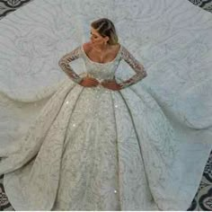 a woman in a white wedding dress standing next to a large piece of fabric with sequins on it