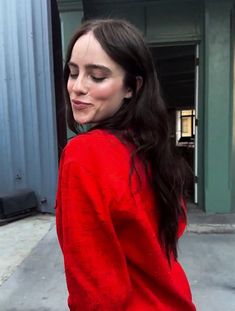 a woman with long dark hair wearing a red sweater