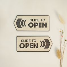 two wooden signs that say slide to open and side to open on white background with dried flowers