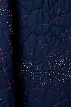 a close up of a quilt on a bed with stars and lines all over it