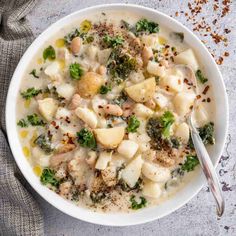 a white bowl filled with pasta and broccoli on top of a gray surface