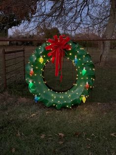 a lighted wreath sitting in the grass near a fence