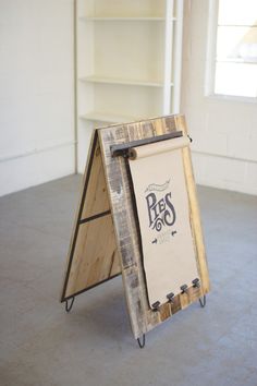 a wooden sign sitting on top of a cement floor next to a book shelf and window