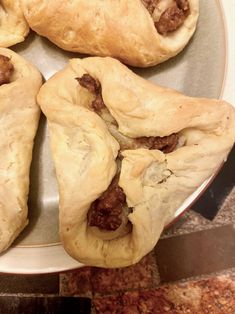 four pastries on a plate with meat in them