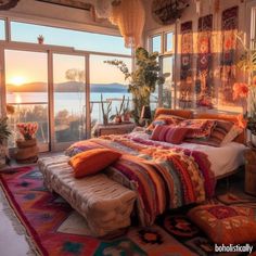 a bedroom with a large bed and lots of pillows on the floor next to windows