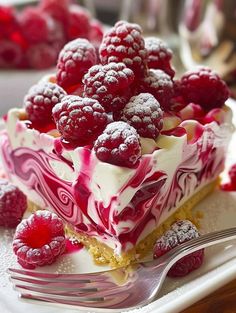 a piece of cake with raspberries and cream on top is sitting on a plate