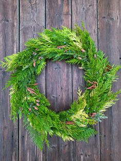 a green wreath is hanging on a wooden wall