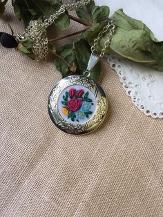 a close up of a necklace on a table with leaves and flowers in the background