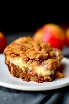 a piece of cake sitting on top of a white plate next to some red apples