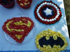 four plates with fruit in the shape of batman and red, white, and blue desserts