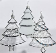 three silver christmas trees with blue beads hanging from the sides on a white background,