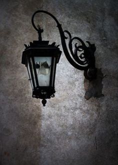 an old fashioned street light on the side of a building with peeling paint and chipped plaster