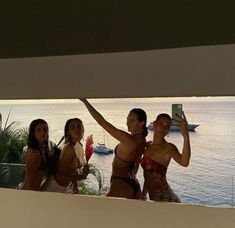 three women taking a selfie in front of the ocean with their cell phones up