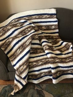 a couch with a blanket on top of it next to a chair and carpeted floor