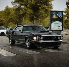 an old muscle car is driving down the street