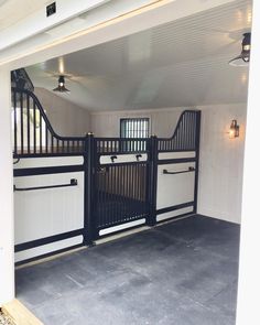 the inside of a horse stable with black and white doors on it's sides