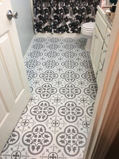 a bathroom with black and white tile flooring next to a shower curtain in the corner