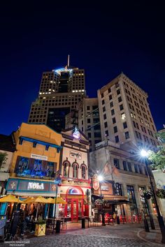 a city street at night with tall buildings in the background