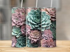 two tumblers with succulents on them sitting next to each other in front of a wooden table