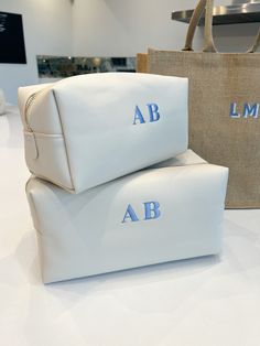 two white bags with the letters ab and b on them sitting on a table next to each other