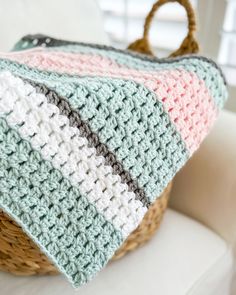 a crocheted blanket sitting on top of a white chair next to a basket