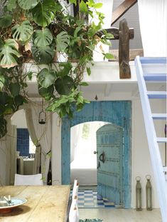 an open door leading to a living room with stairs and potted plants on the table