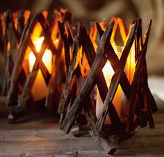 some candles that are sitting on top of a wooden table with wood sticks in front of them